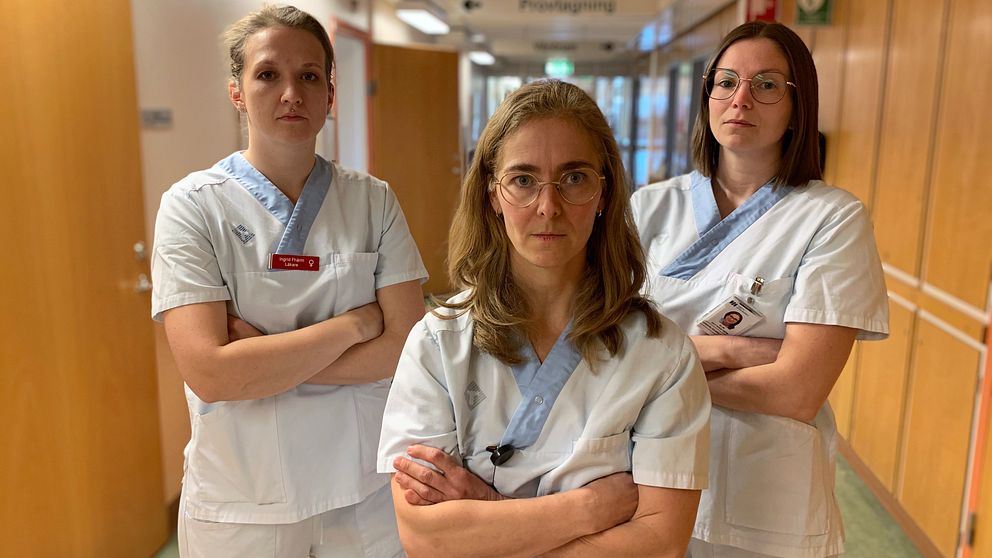 Tre kvinnor i sjukhusuniform står med korsade armar och tittar bestämt in i kameran.
