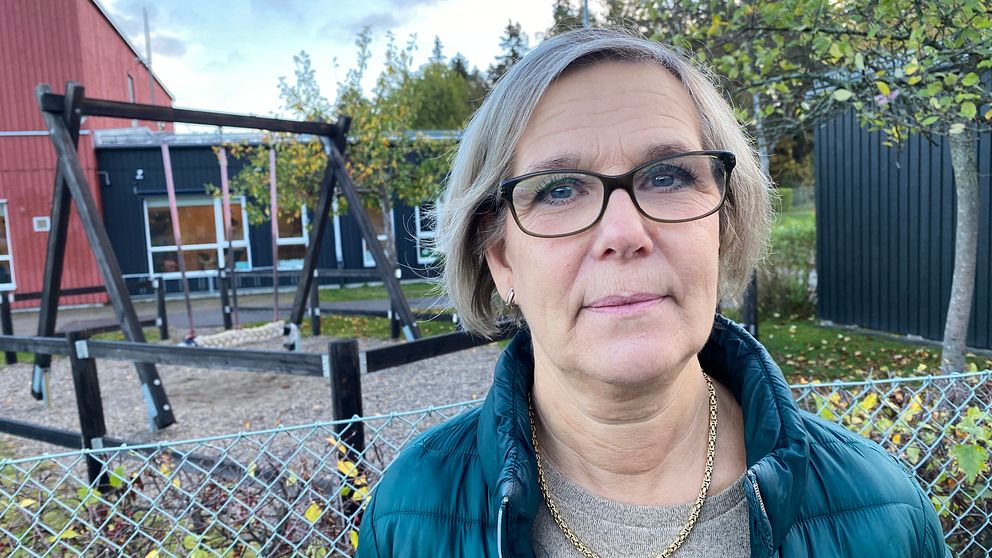 Carin Lindberg i grön täckjacka står utanför förskolans lekpark.