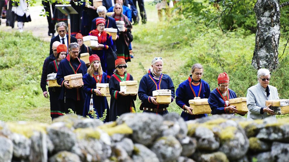 Procession mot gravplatsen där de 25 näveraskar som innehåller kvarlevor ska jordfästas under återbegravningen på försoningsceremonin vid Gammplatsen, Lycksele 9 augusti 2019