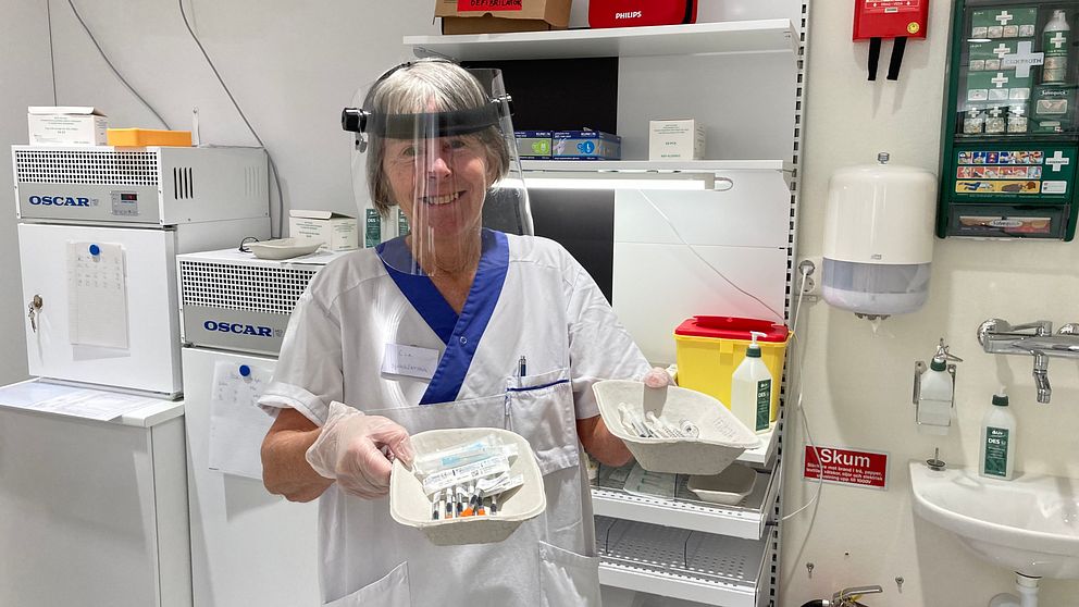 Sjuksköterskan Cia Karlsson håller upp lådor med färdiga vaccinsprutor.