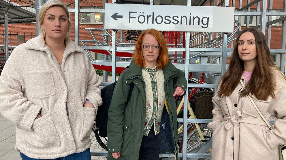 På bilden står tre kvinnor på rad bredvid varandra. De är barmorskestudenter och står framför en skylt där det står ”förlossning”. Alla tre tittar in i kameran.