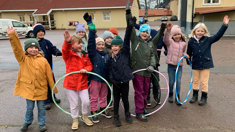 Glada skolbarn med rockringar på skolgården