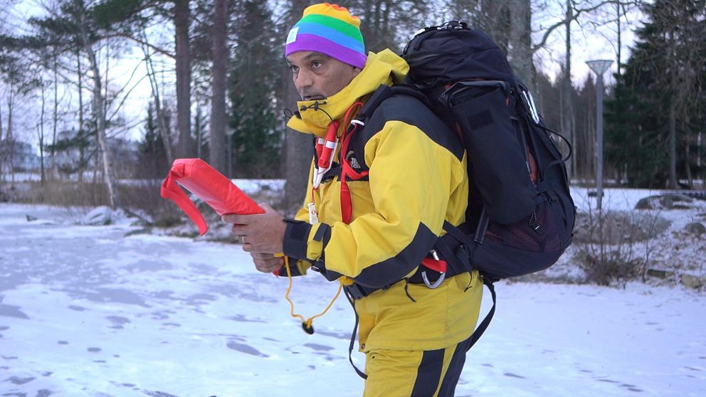 Man med ryggsäck och isdubbar står på isen för att lära ut issäkerhet.