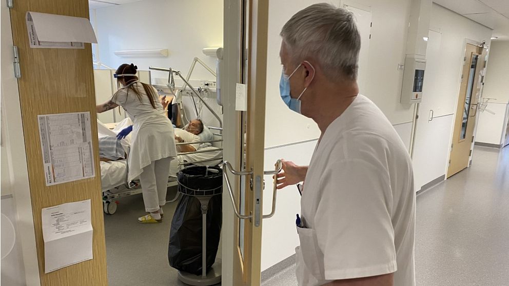 Läkare öppnar dörr på medicinkliniken i Malmö. Sjuk covidpatient ligger i sängen.
