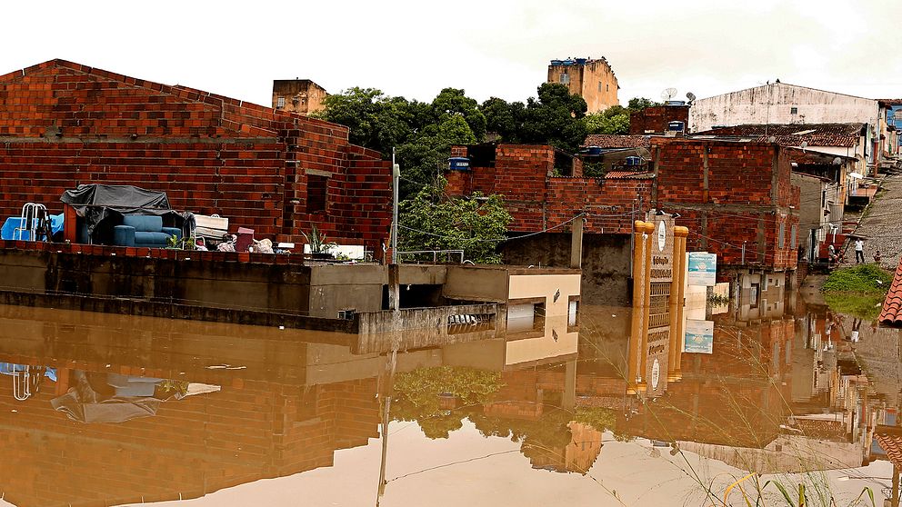 Familjer placerar möbler på taket av sina hus på grund av översvämningar orsakade av kraftiga regn i staden Itapetinga, i södra delen av delstaten Bahia, Brasilien under söndagen.
