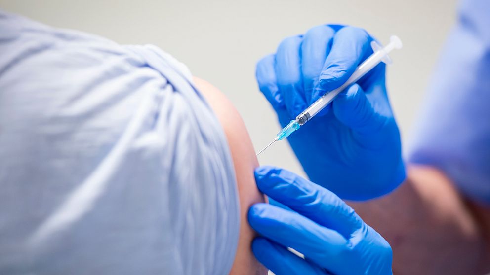 En vaccinatör ger en man en dos vaccin.