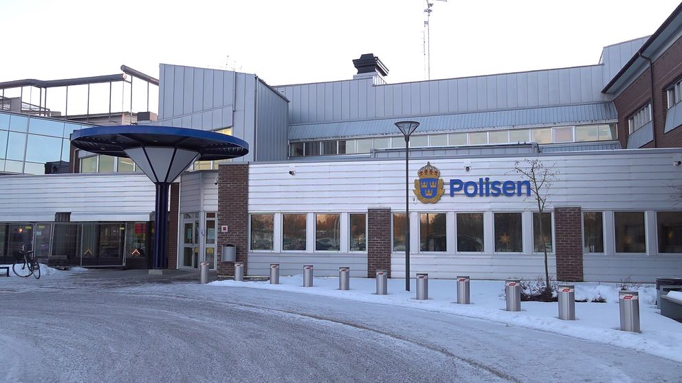 En ljus byggnad med en polisskylt på fasaden.