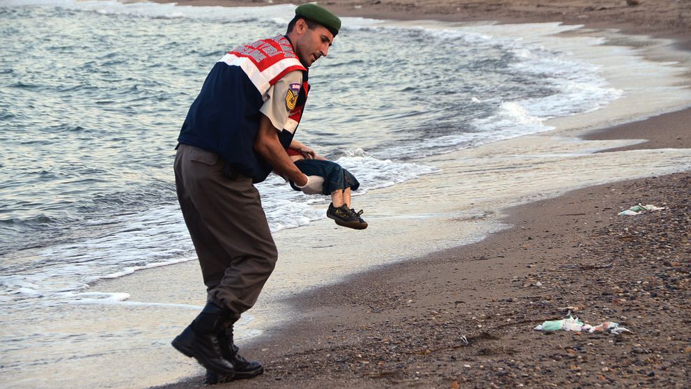 En turkisk militärpolis bär bort den döda pojken.