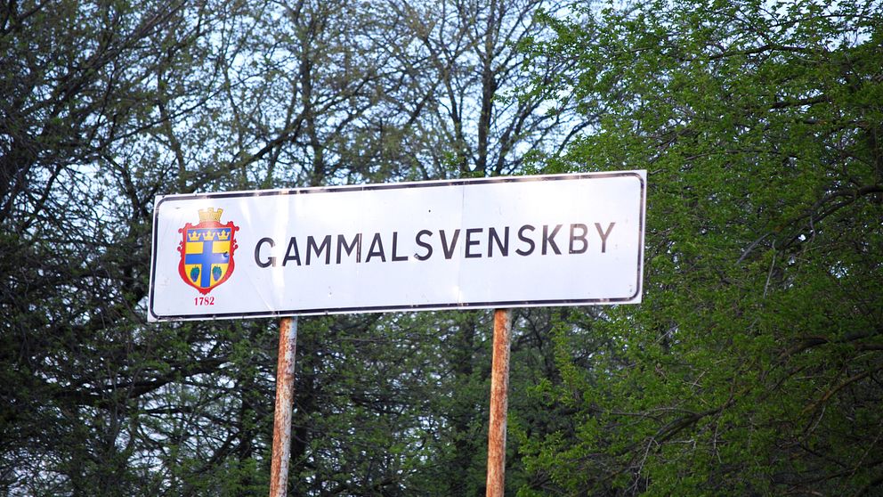 Skylt med texten ”Gammalsvenskby” i grönskande omgivning.