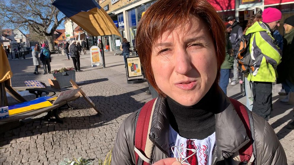Människor på torget, klädda i vinterkläder, delvis skuggade av marknadsstånd.