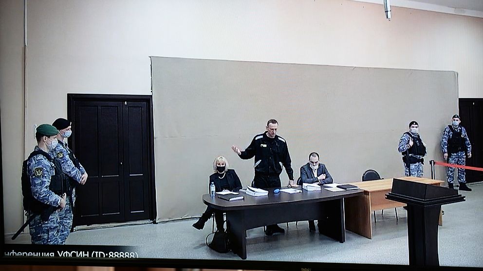 Aleksej Navalnyj (stående i mitten) i domstolen i den straffkoloni där han sedan tidigare avtjänar sitt straff, i Pokrov öster om Moskva.