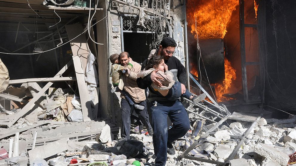 Barn räddas ur ett hus som utsatts för en bombattack i Aleppo i Syrien.