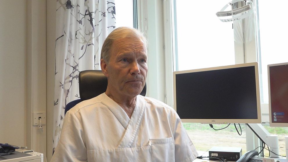 Åke Åkesson i vita läkare kläder stirrar