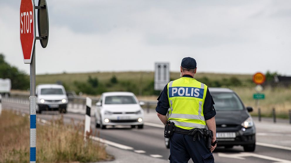 En polis står längd med vägen E65 och bilar kör förbi.