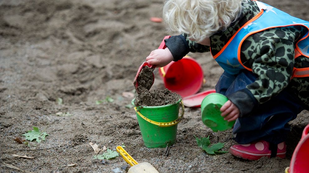 Barn gräver i sanden utanför förskola.