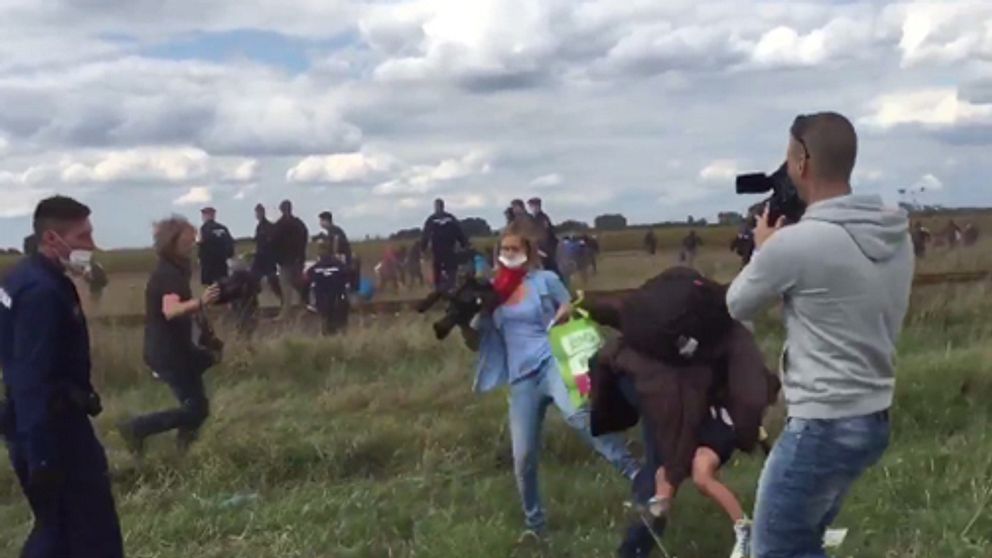 En ungersk journalist fäller krokben för en flyende man på ett fält utanför staden Röszke.