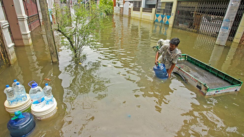 En man levererar dricksvatten längs en översvämmad gata i staden Sylhet i nordöstra Bangladesh.