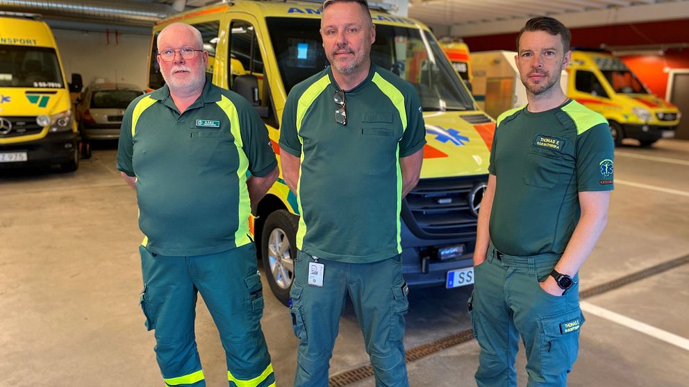 Kåre Karlsson, Jonas Åsberg och Thomas Erlandsson i gröna ambulanspersonalkläder framför gula ambulanser