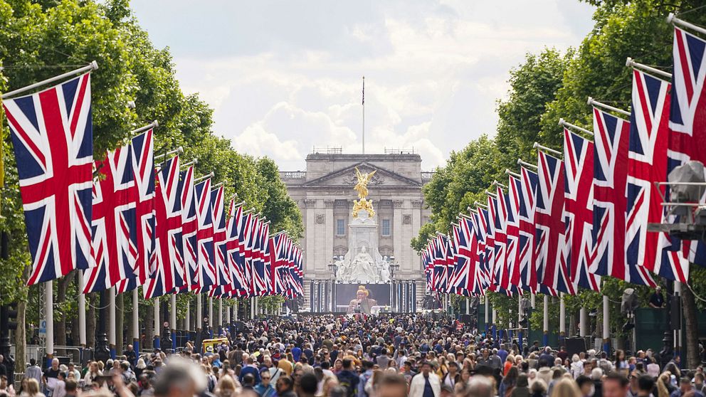 Människor samlade på gata i London. På båda sidorna hänger flera brittiska flaggor.