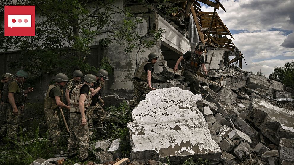 Ukrainska soldater står vid en bombad byggnad.