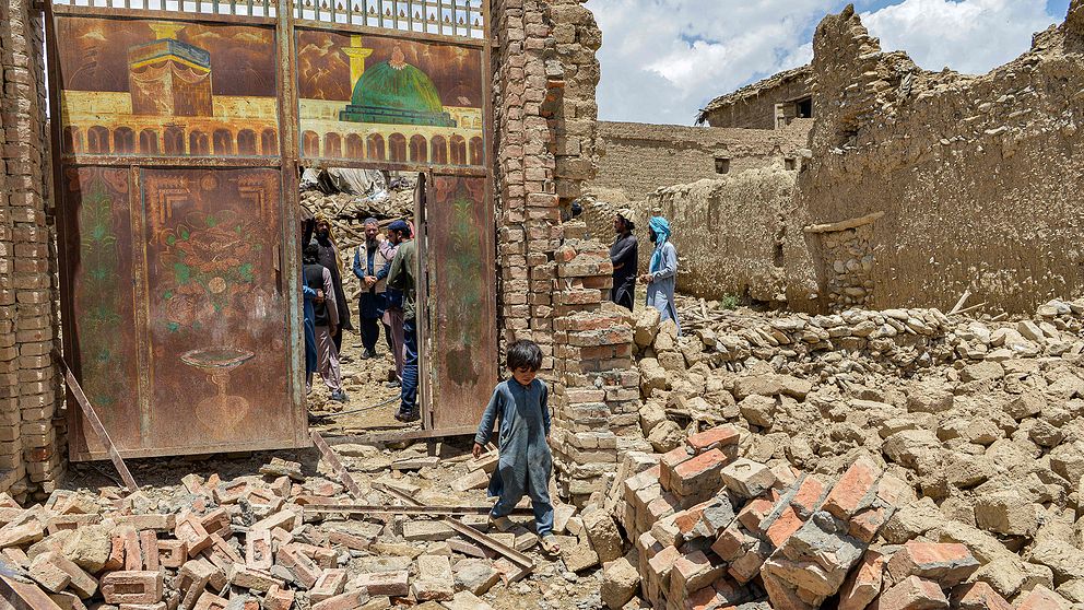 Pojke som går i rasmassor efter jordbävning i Afghanistan.