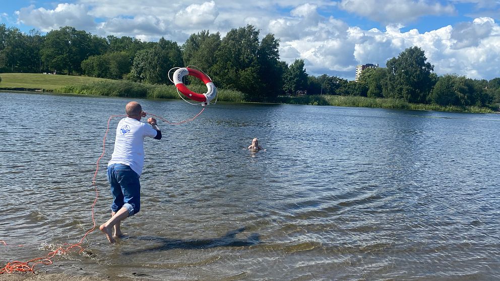 Jonny Darabant, vice ordförande i SLS Sörmland, kastar ut en livboj från en strandkant ut till en flicka som befinner sig i sjön.