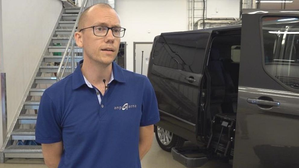 en man intervjuas i en verkstadslokal, bredvid en minibuss.