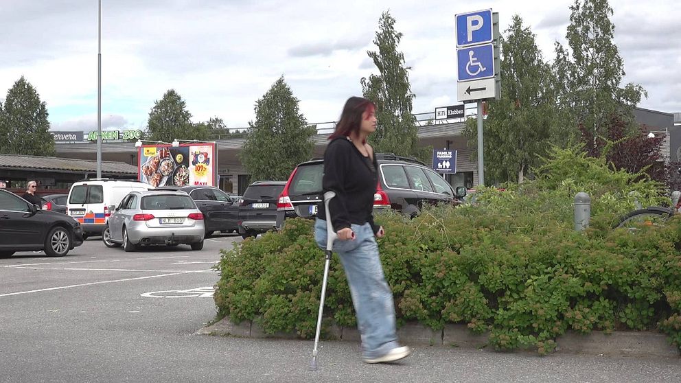En tjej med ett ben hoppar på kryckor på en parkering i Umeå.