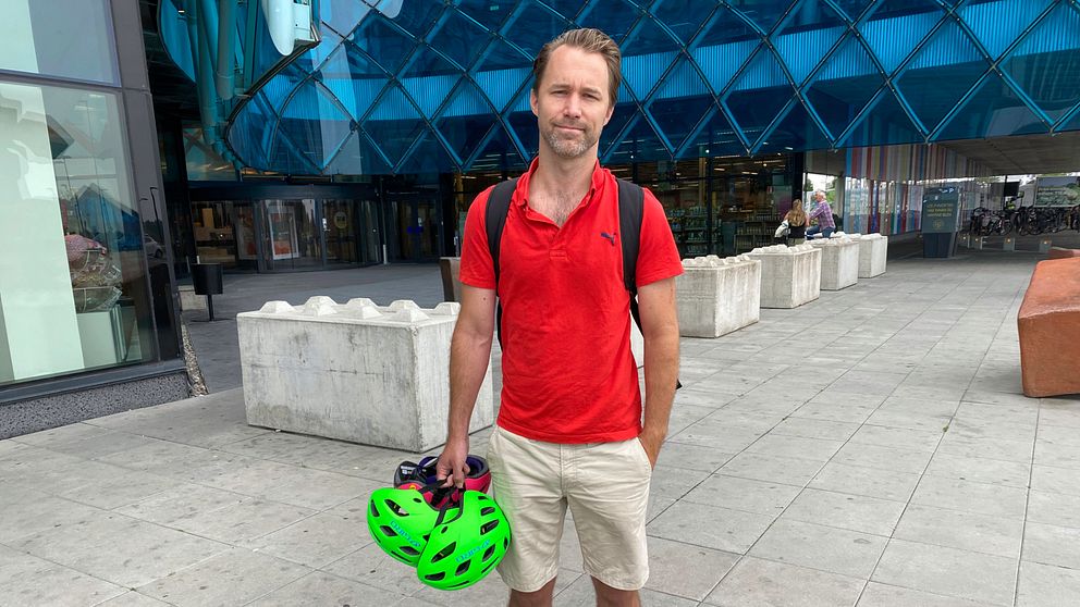 Joakim Nyström tittar in i en cykelvagn, där sitter två små pojkar med varsin grön cykelhjälm.