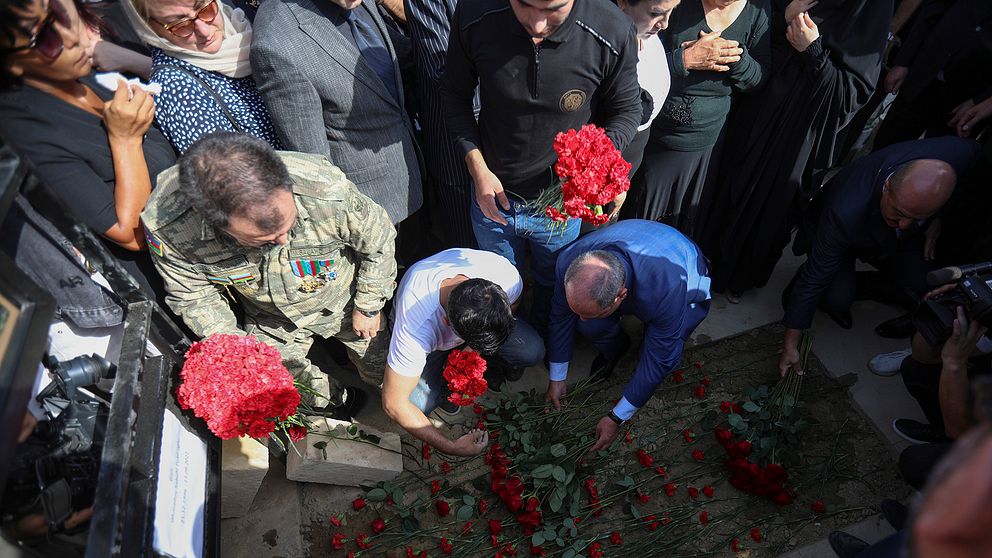 Azerier placerar blommor vid en militärgrav i Azerbajdzjan under en massbegravning av azeriska militärer som dödades under sammandrabbningar med armeniska trupper vid gränsen till Armenien.