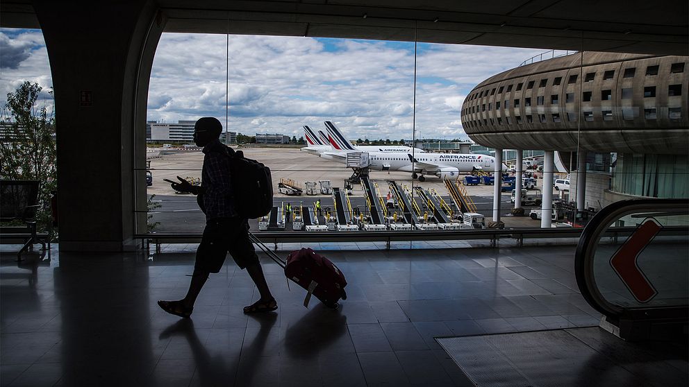 En man drar sin resväska genom terminalen på flygplatsen Roissy utanför Paris.