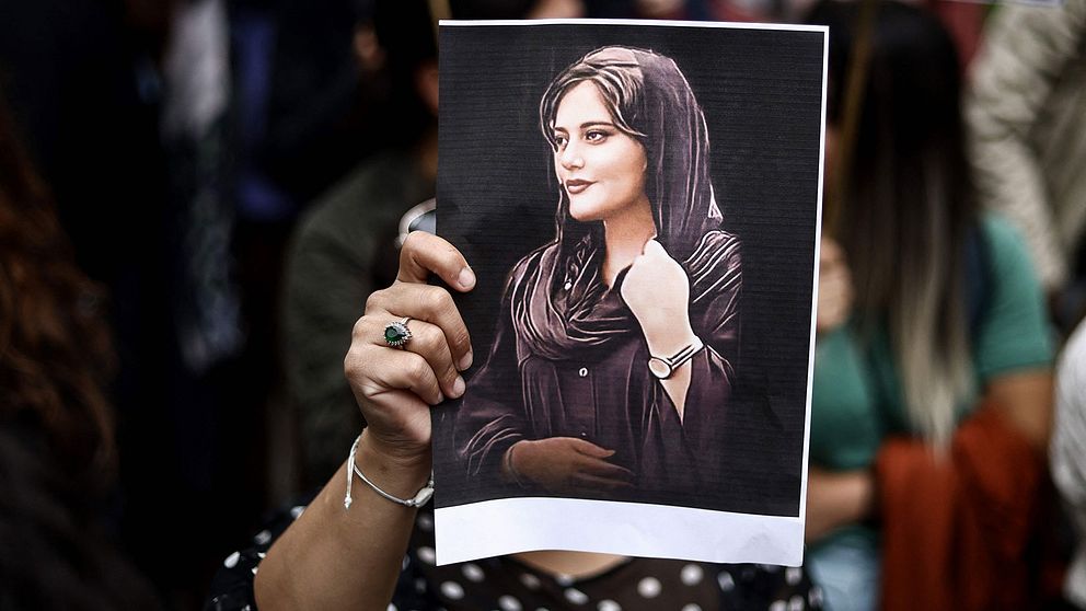 En demonstrant håller upp en teckning av Mahsa Amini.