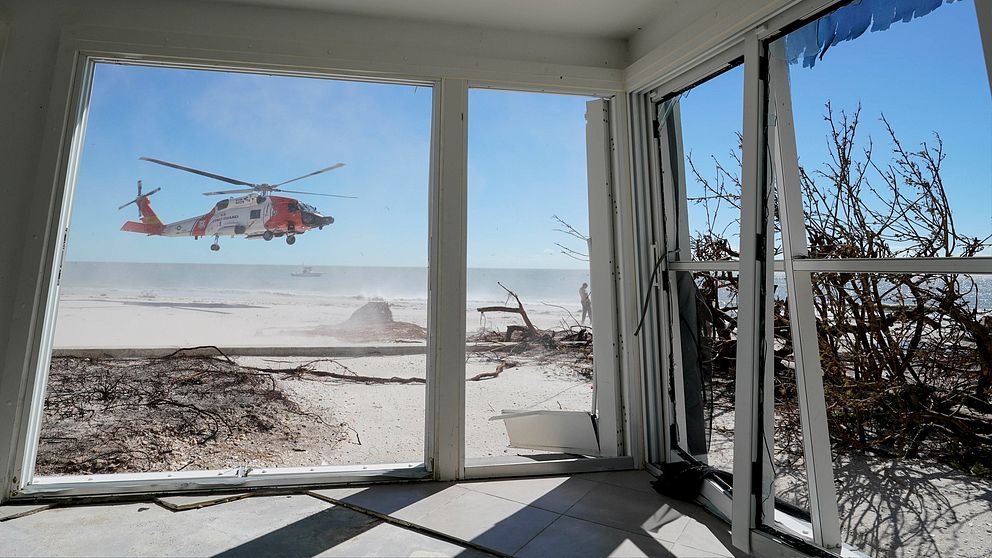 Amerikanska kusthelikoptern flyger lågt och syns genom ett hem på Sanibel Island.