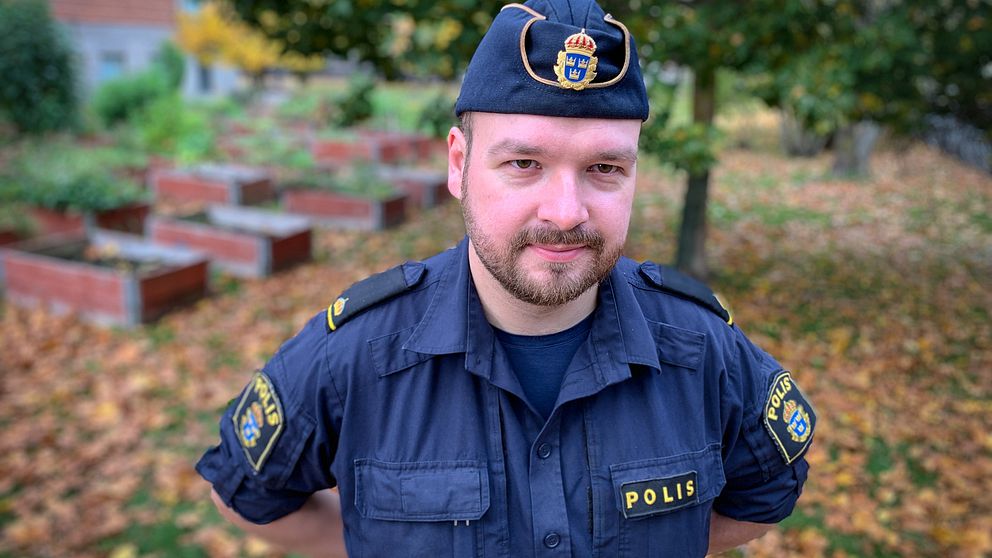 porträttbild på polisen Benjamin Sjöberg – en man polisuniform och polismössa, utomhus på hösten