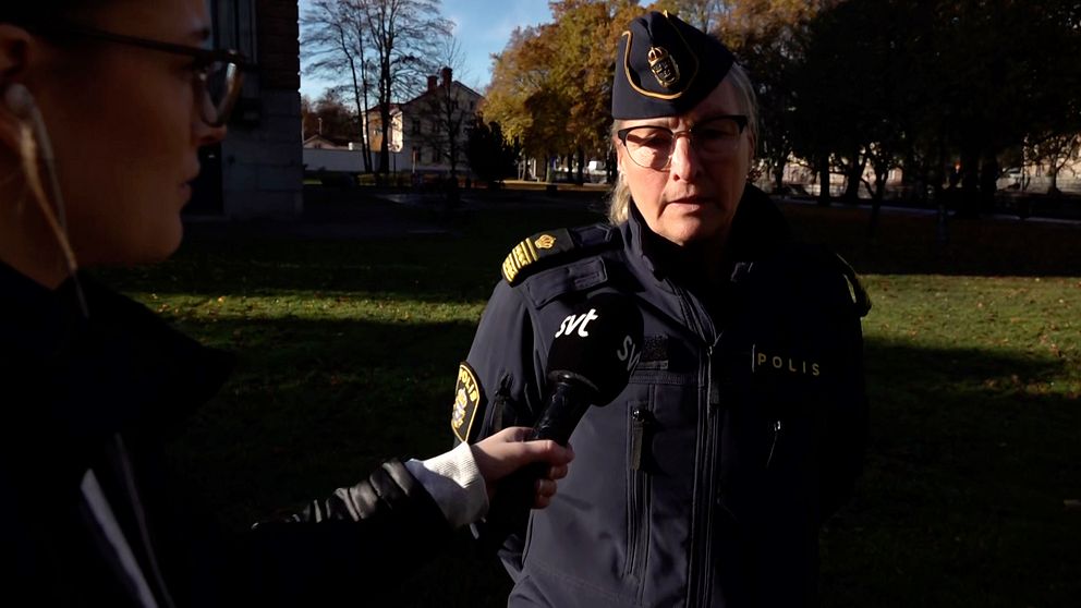 medelålders kvinna i polisens uniform och mössa intervjuas i en park