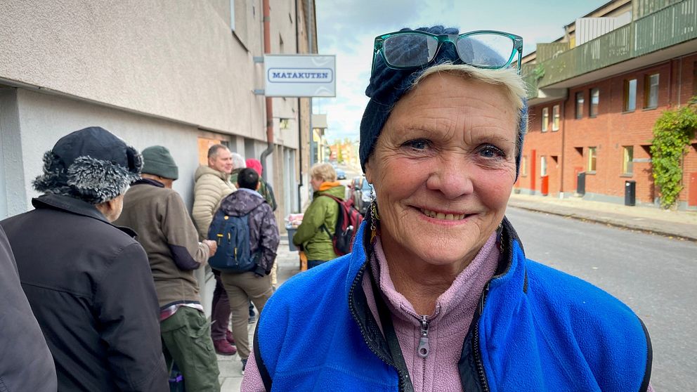 En stående hon leende kvinna (Eva Huss) vid Matakutens kö i Gävle.