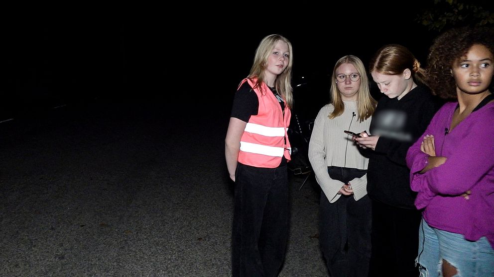 Fyra unga tjejer som står på en mörk gata.