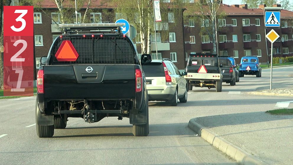 Bild på A-traktorer med varningstriangel som kör på en asfalterad väg. Hus i bakgrunden.