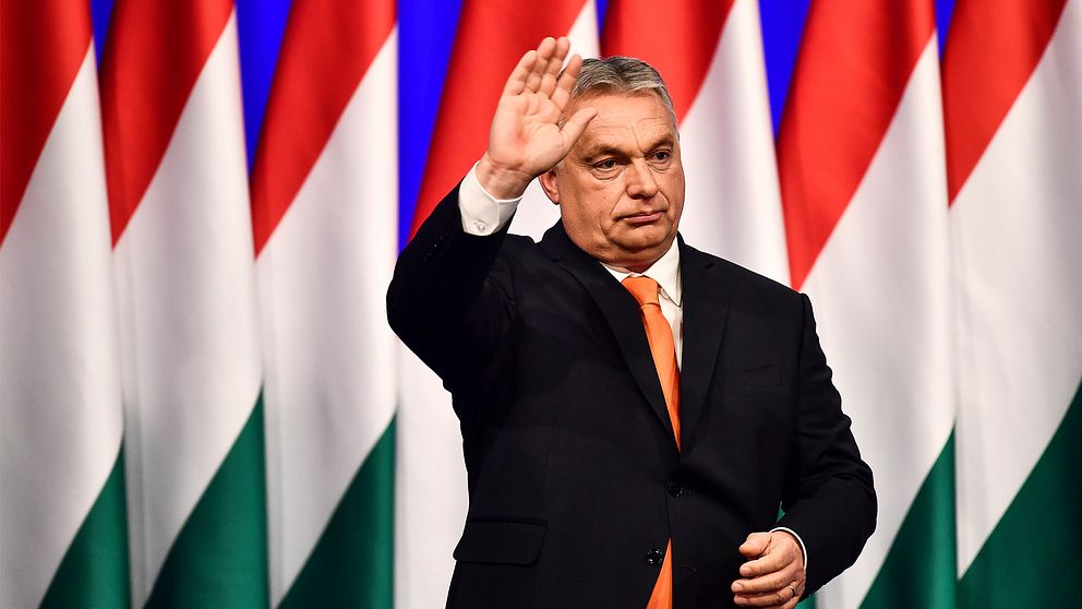 Bilden föreställer Ungerns premiärminister Viktor Orbán som vinkar framför ungerska flaggor.