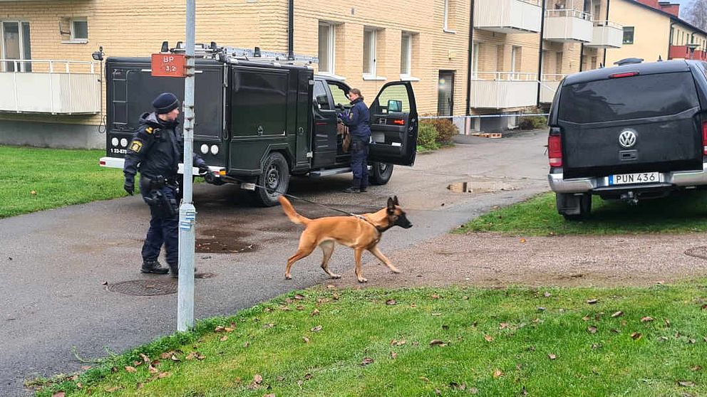 Polis och polishund utanför bostadsfastighet i Askersund.