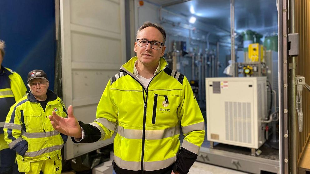 Daniel Ragnvaldsson från företaget Envix förklarar hur de renar läkemedel ur avloppsvattnet i Strömsund. Daniel är klädd i gul varseljacka och står framför en container där dörrarna är öppna och man ser teknisk utrustning i containern.