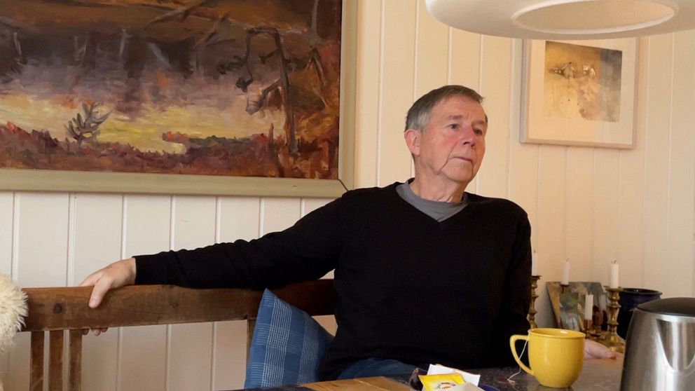 Göran Lilljeqvist i svart tröja sitter på en köksbänk med ena handen på ryggstödet.
