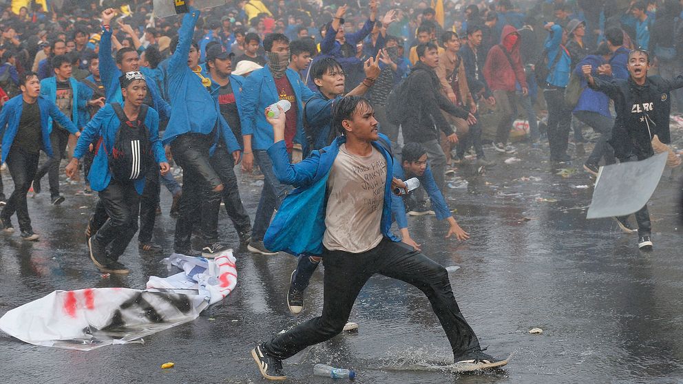 Indoneser som protesterar, en man laddar inför att kasta flaskor.