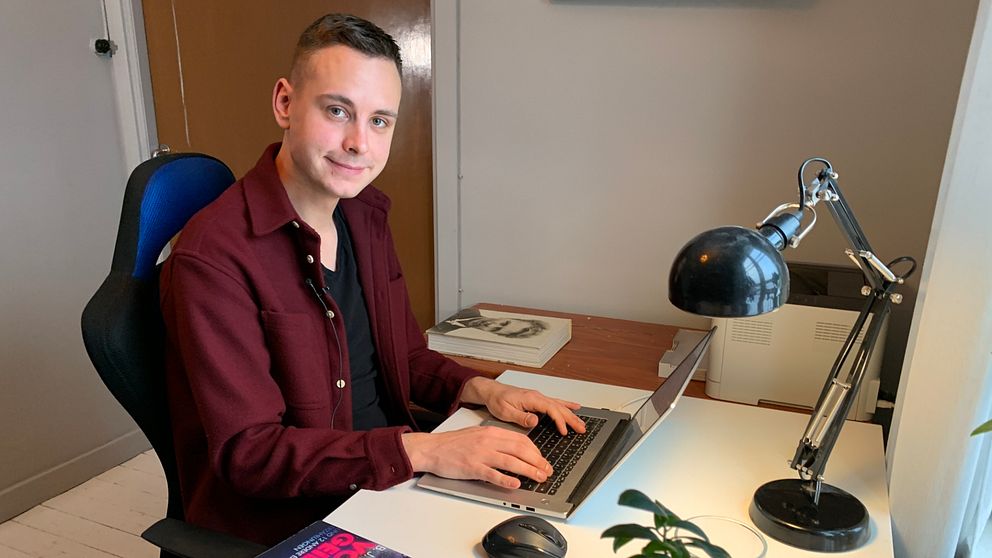 Författaren Backolars Johan Hermansson sitter vid sitt skrivbord framför sin laptop