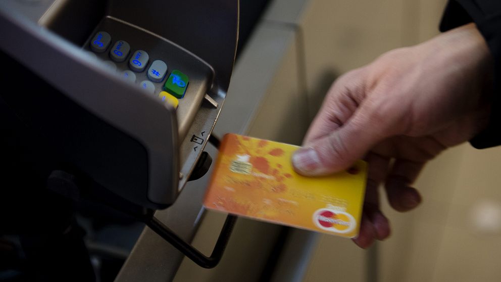 En person håller fram ett betalkort mot en kortmaskin.