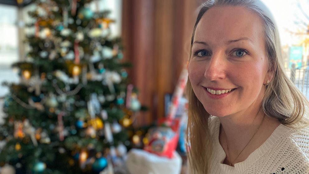 Bild på Eskilstunabon Jannica Sjöstedt. Hon har rågblont hår och tittar in i kameran. I bakgrunden skymtar en julgran som det ligger julklappar under.
