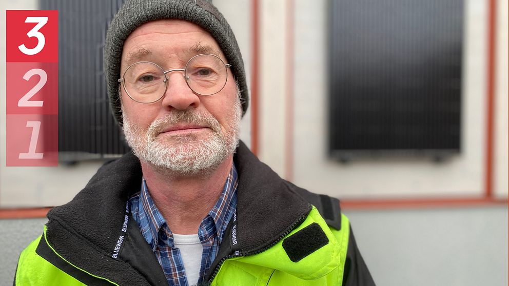 Porträttbild på Per Ekstorm, energi- och klimatrådgivare i Eskilstuna kommun. Han har på sig varseljacka, mössa och runda glasögon. I bakgrunden skymtar två solcellspaneler.