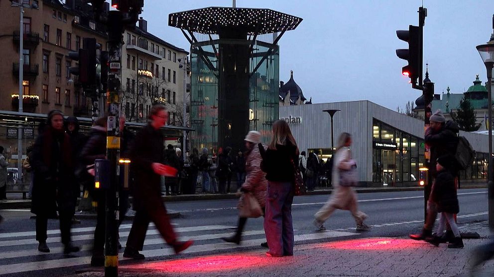 Fotgängare går mot rött ljus vid det bevakade övergångsstället Odenplan i centrala Stockholm.