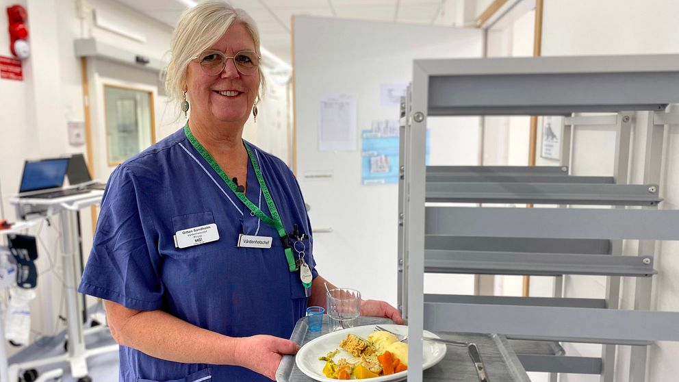 Gittan Sandholm, vårdenhetschef för planerad kirurgi, håller i en bricka där det finns en tallrik med mat som lagats i sjukhusets eget kök.