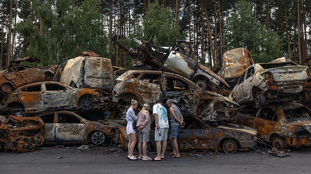 Boende i Irpin undersöker en hög av brända bilar som förstörts under ryska attacker i Irpin, sommaren 2022.